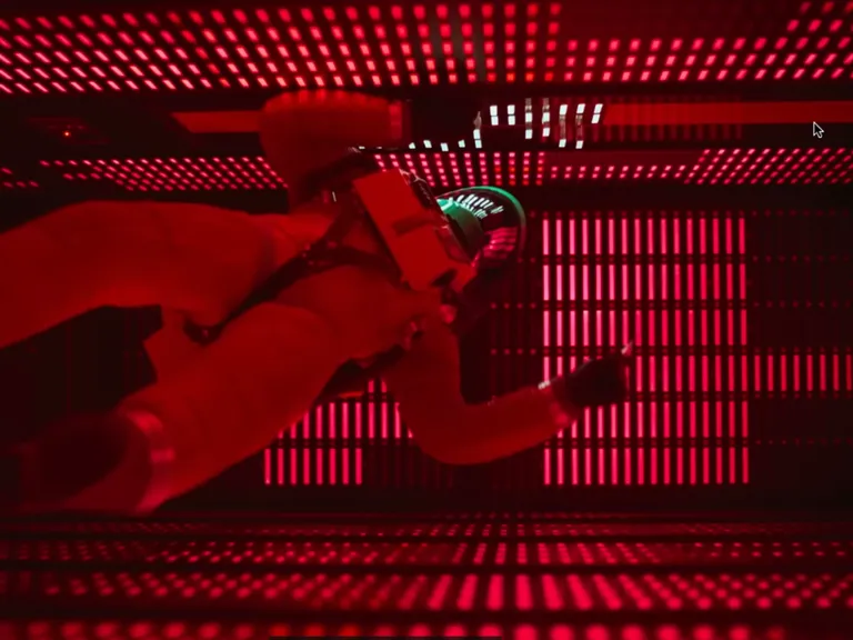 Szene aus dem Film Space Odysee: Dave in orangem Anzug schwebt futuristischem Raum. Das Bild steht symbolisch für die KI-Dystopie.
